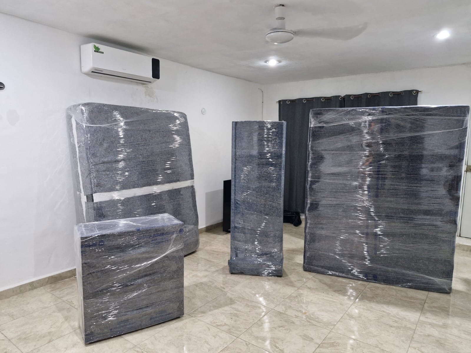 Piezas de mobiliario envueltas con mantas y película plástica en el interior de una vivienda