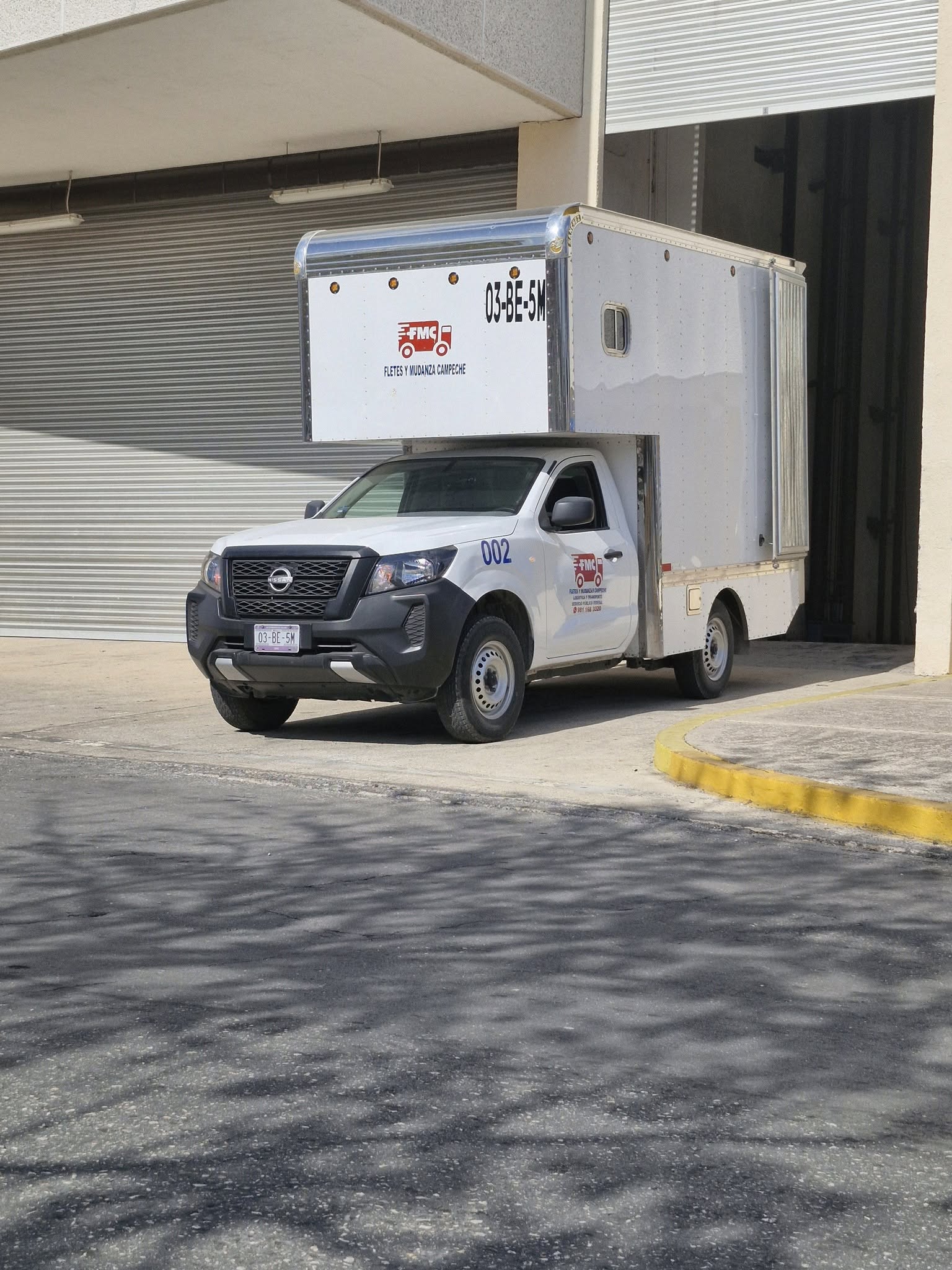 Unidad de transporte de Fletes y Mudanzas Campeche, fotografiada frente a una bodega